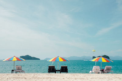 Scenic view of sofas and umbrellas on the beach against blue sky