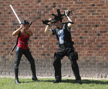 Full length of men standing on brick wall