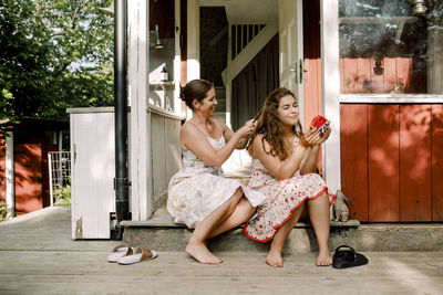 Full length of smiling woman sitting outdoors