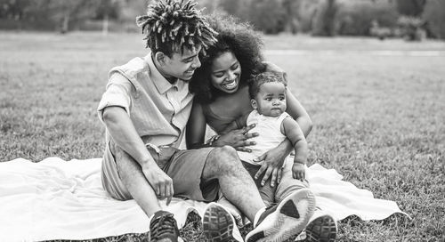 Smiling parents looking at daughter while sitting in park