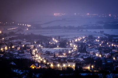 High angle view of illuminated town against sky at night