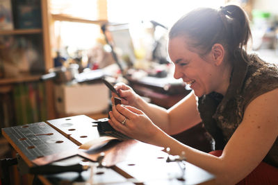 Girl master processes the metal copper plate on the workbench in the home workshop, soft focus 
