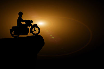 Silhouette man riding bicycle against sky during sunset