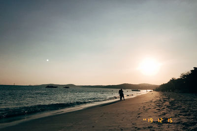 Silhouette people on beach against sky during sunset