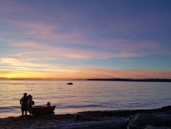 Silhouette people on beach against sky during sunset