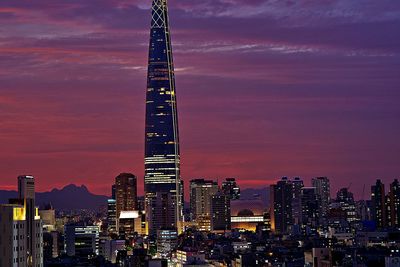 Illuminated modern buildings in city against sky