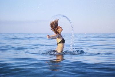 Woman standing in sea against sky