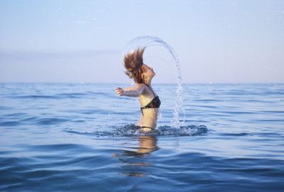 Woman standing in sea against sky