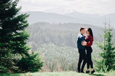 Side view of young couple standing face to face in forest