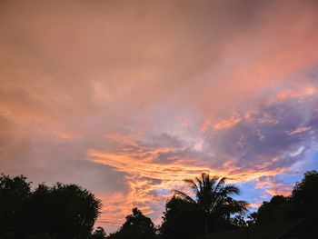 Low angle view of silhouette trees against dramatic sky