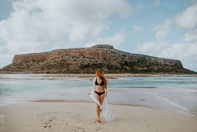 Rear view of woman on beach against sky