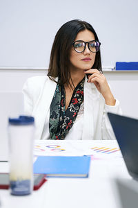 Portrait of young woman using mobile phone while sitting on table