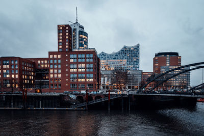 River by buildings in city against sky