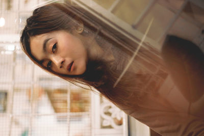 Portrait of young woman looking through window