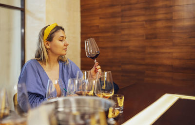 Portrait of young woman holding wineglass on table