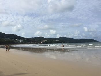 Scenic view of beach against cloudy sky