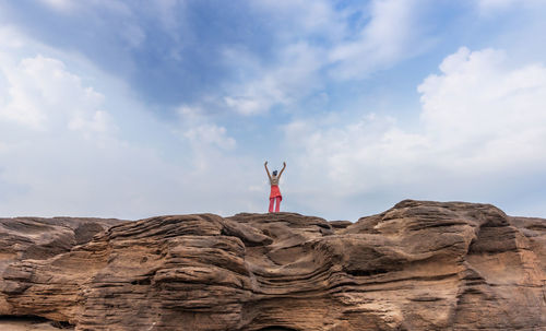 Rear view of man standing on rock against sky