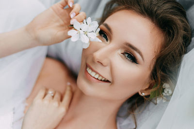 Beautiful bride in a wedding dress walks in a blooming apple-tree park in spring