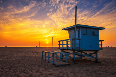 Lifeguard hut on beach against sky during sunset