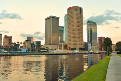 Modern buildings by river against sky in city