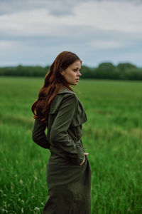 Contemplative woman with hand in pocket at field