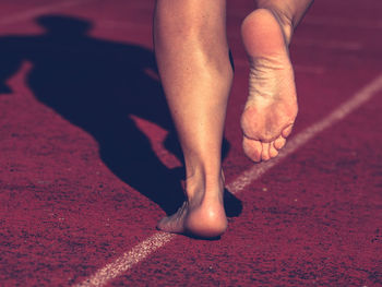 Solid bare feet of hard training woman. a woman runs along soft surface of a running track in pants