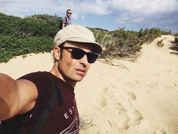 Portrait of young man wearing sunglasses standing at beach