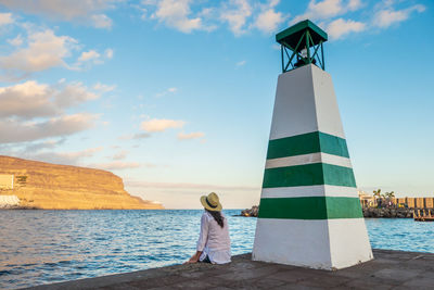 Young woman looking the sea by the lighthouse in puerto de mogan, gran canaria, canary island, spain