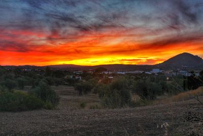 Scenic view of field against dramatic sky during sunset