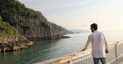 Rear view of man looking at sea against sky