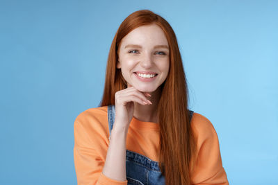 Beautiful woman with hand on chin against blue background