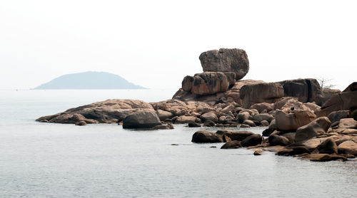 Rocks in sea against clear sky