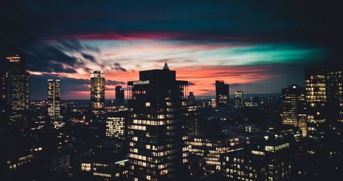 Illuminated cityscape against sky at sunset