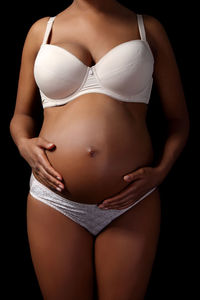 Midsection of woman standing against black background