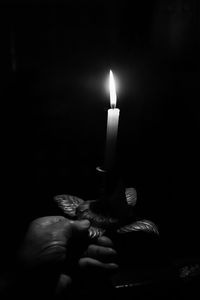 Close-up of hand holding candles in darkroom