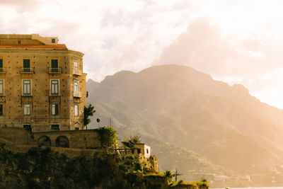 Building by mountain against sky at morning