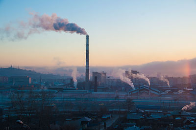 Smoke emitting from factory against sky