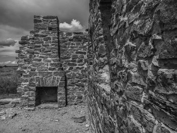 Old stone wall by building against sky