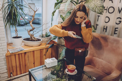 Young woman holding food while sitting on table