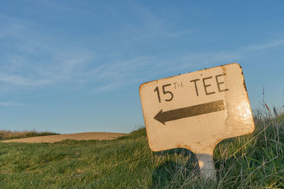 Information sign on field against sky