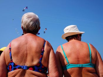 Rear view of friends on beach against sky