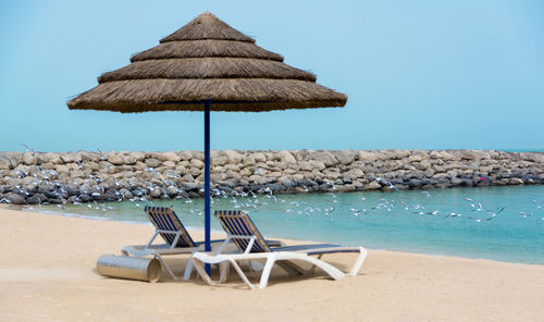 Chair on beach against blue sky