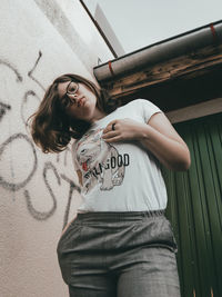 Portrait of young woman standing against wall