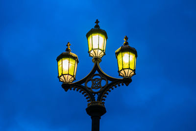 Low angle view of illuminated gas light against blue sky at dusk
