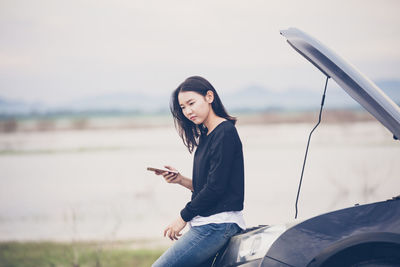 Thoughtful woman leaning on breakdown car