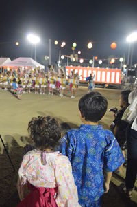 Rear view of people on illuminated street at night