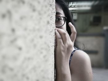 Close-up of woman looking away by wall