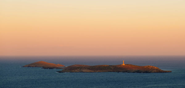 Scenic view of an island against sky during sunset