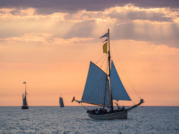 Sailboat sailing on sea against sky during sunset