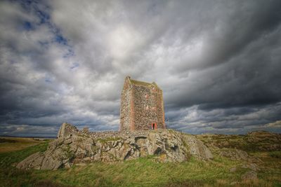 Old ruined building on field against sky